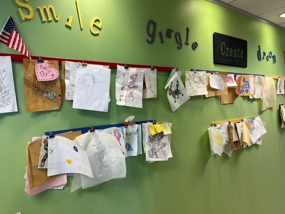 Green wall with children's artwork clipped to red/blue lines. 