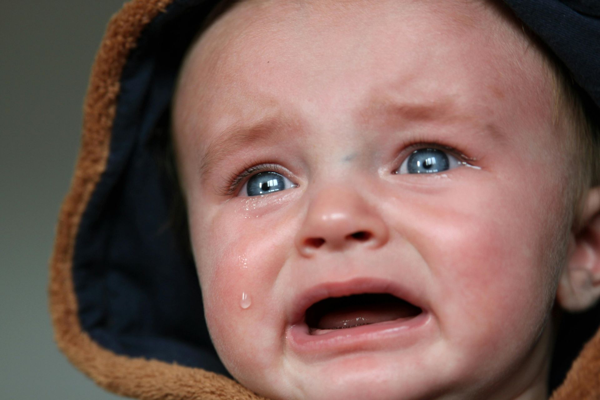 Crying child with a hood on.