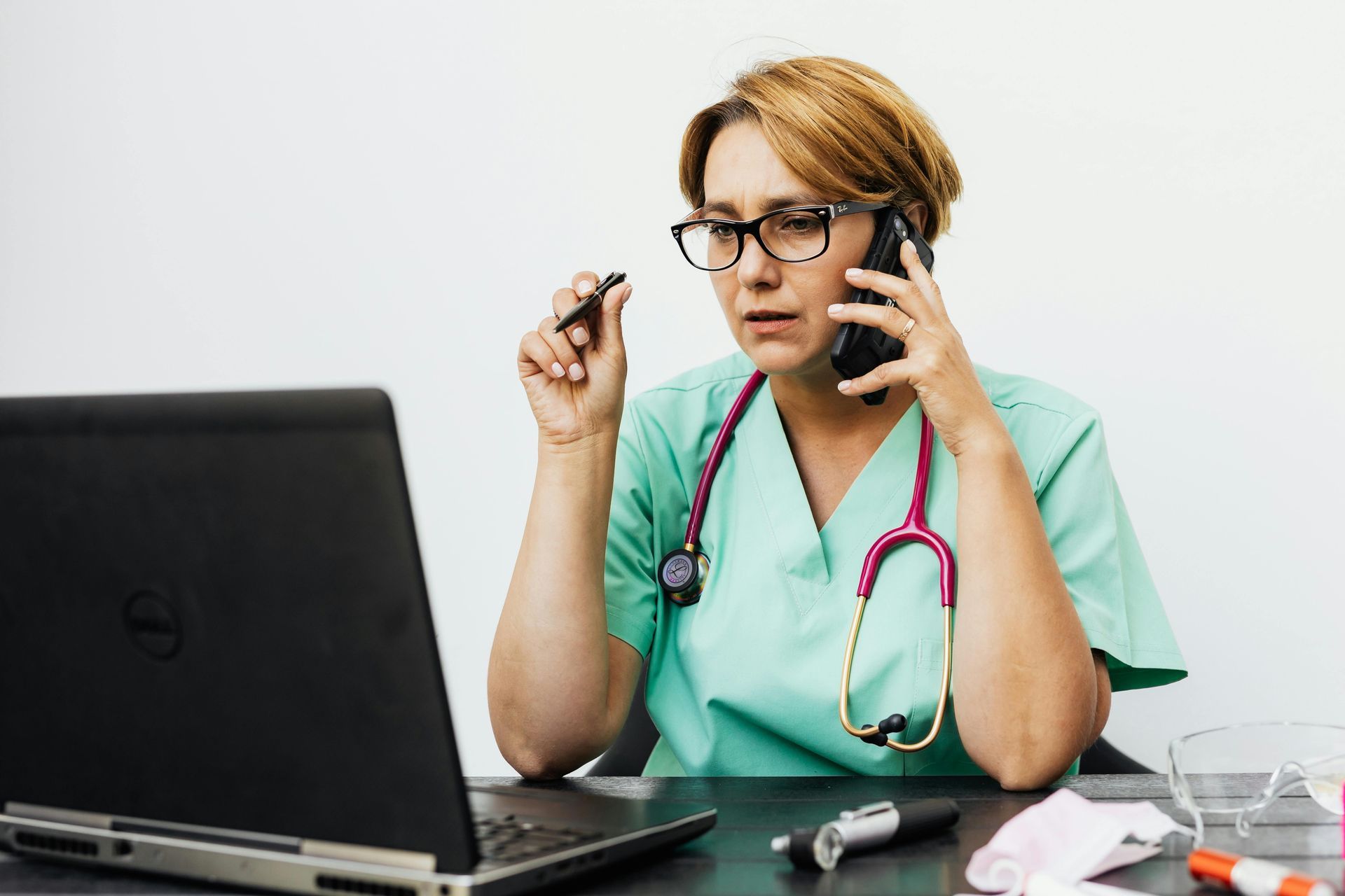 Female medical professional on the phone looking at a computer screen.