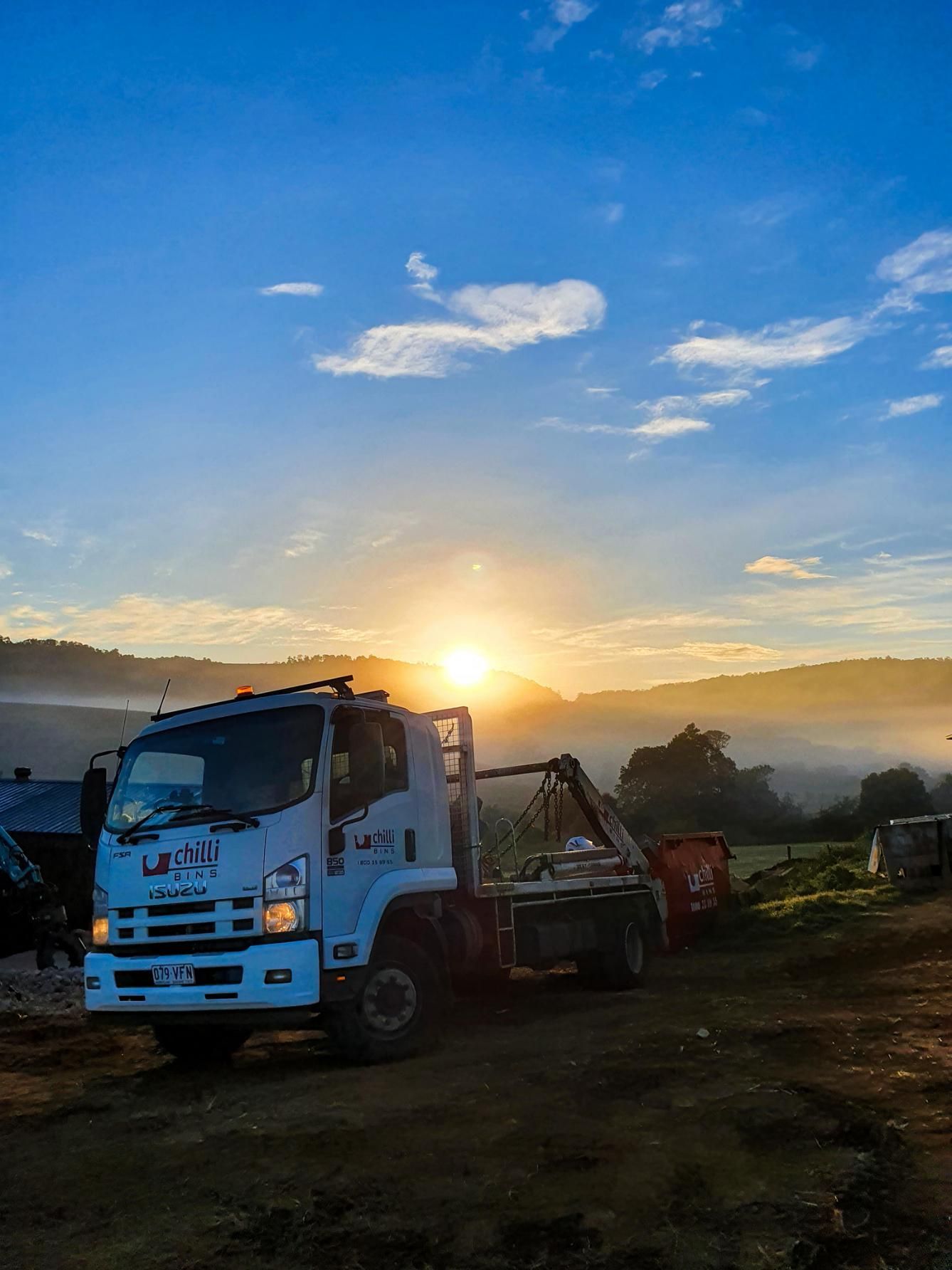 A Truck Is Parked in A Field with A Sunset in The Background — Chilli Bins Skip Bins in Glenview, QLD