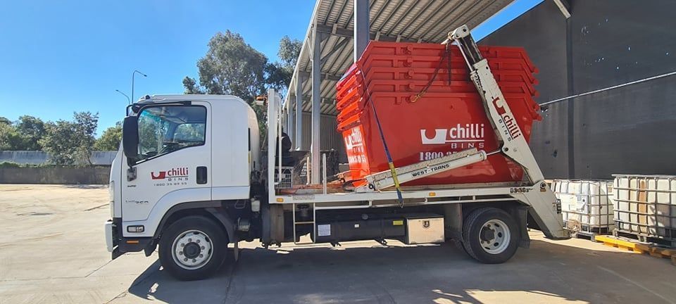 White Truck With Red Waste Bins in an Industrial Setting. Bright Day — Chilli Bins Skip Bins in Glenview, QLD
