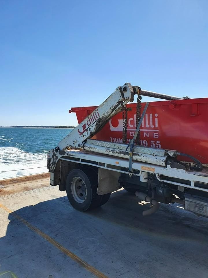 A Red and White Truck Is Parked Next to The Ocean — Chilli Bins Skip Bins in Glenview, QLD