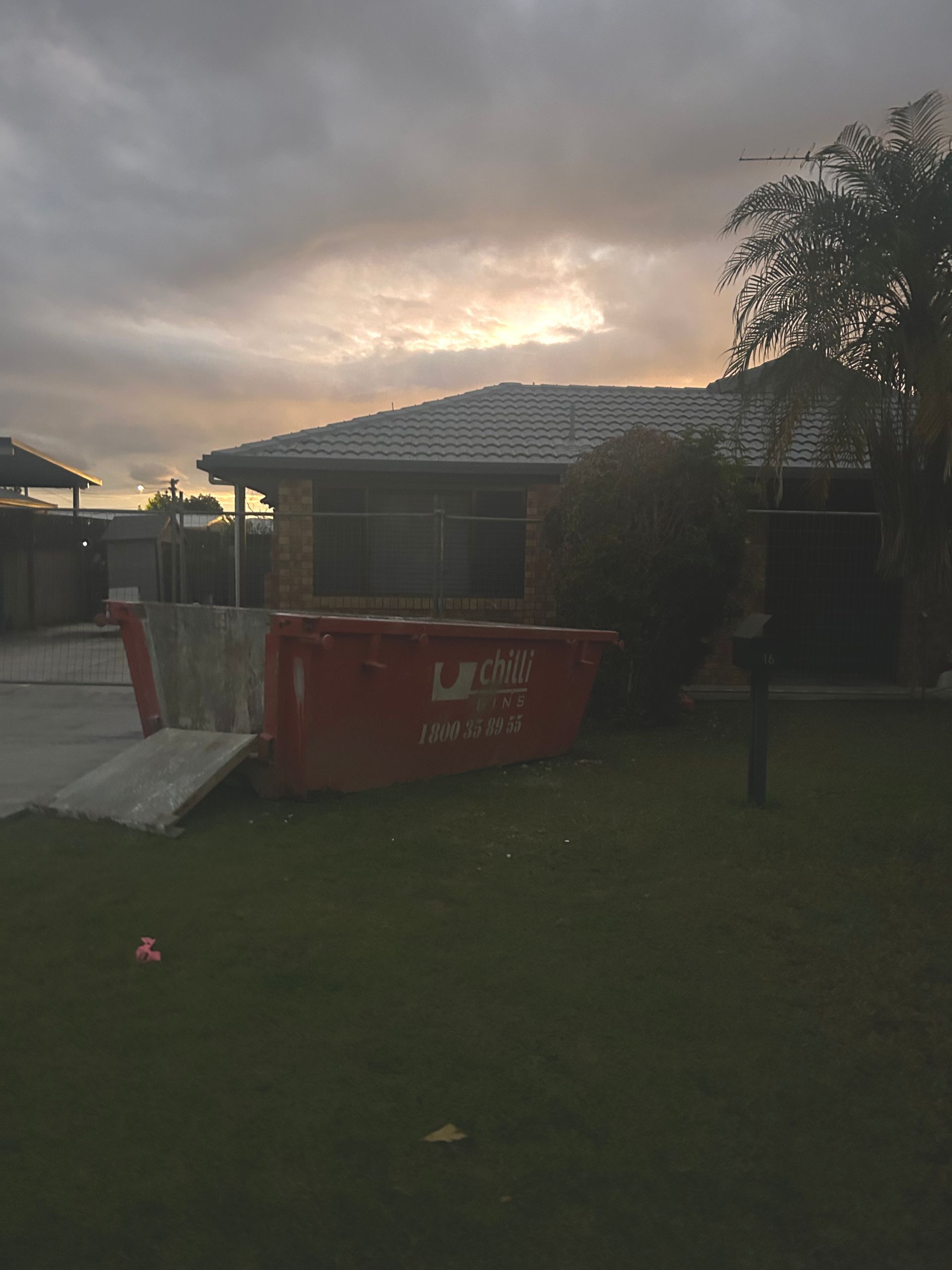 Red Skip Bin on Lawn Outside House — Chilli Bins Skip Bins in Glenview, QLD