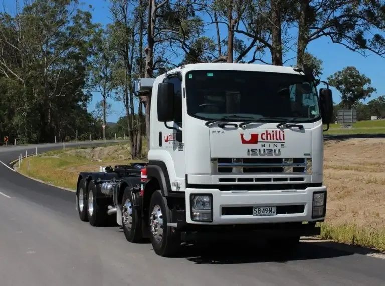 Branded Business Skip Bin Truck Driving on Road Chilli Bins Skip Bins in Glenview, QLD