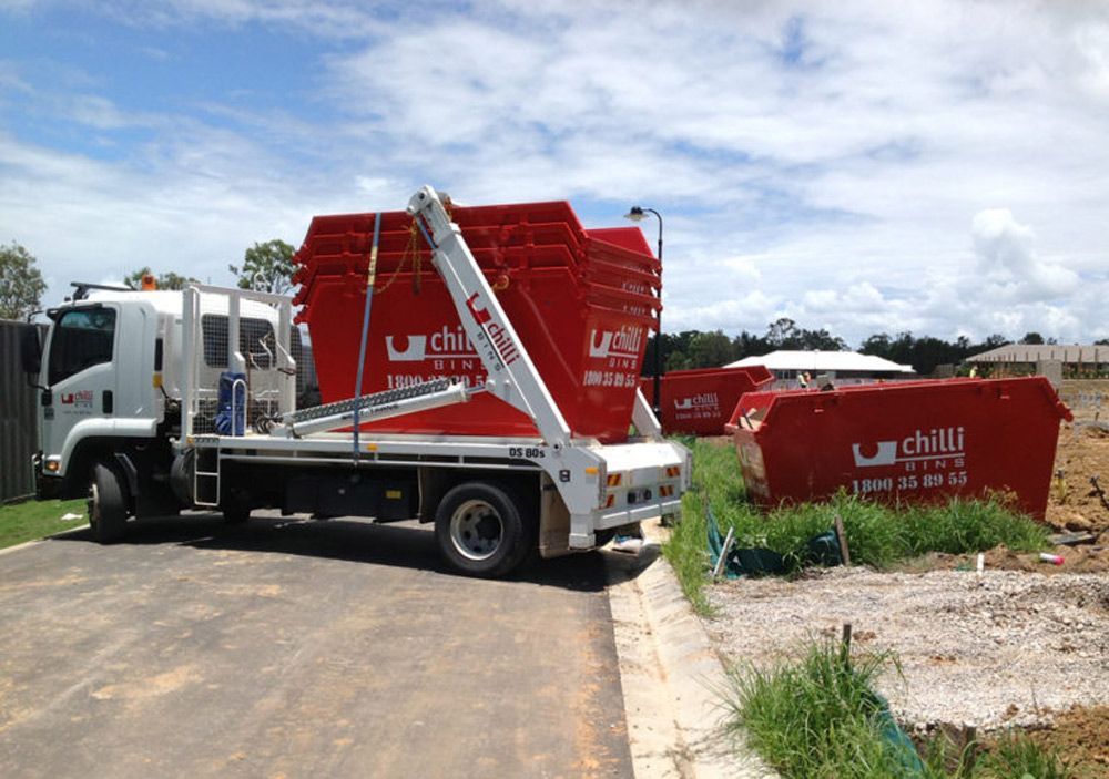 Red Skip Bins Loaded On A Vehicle