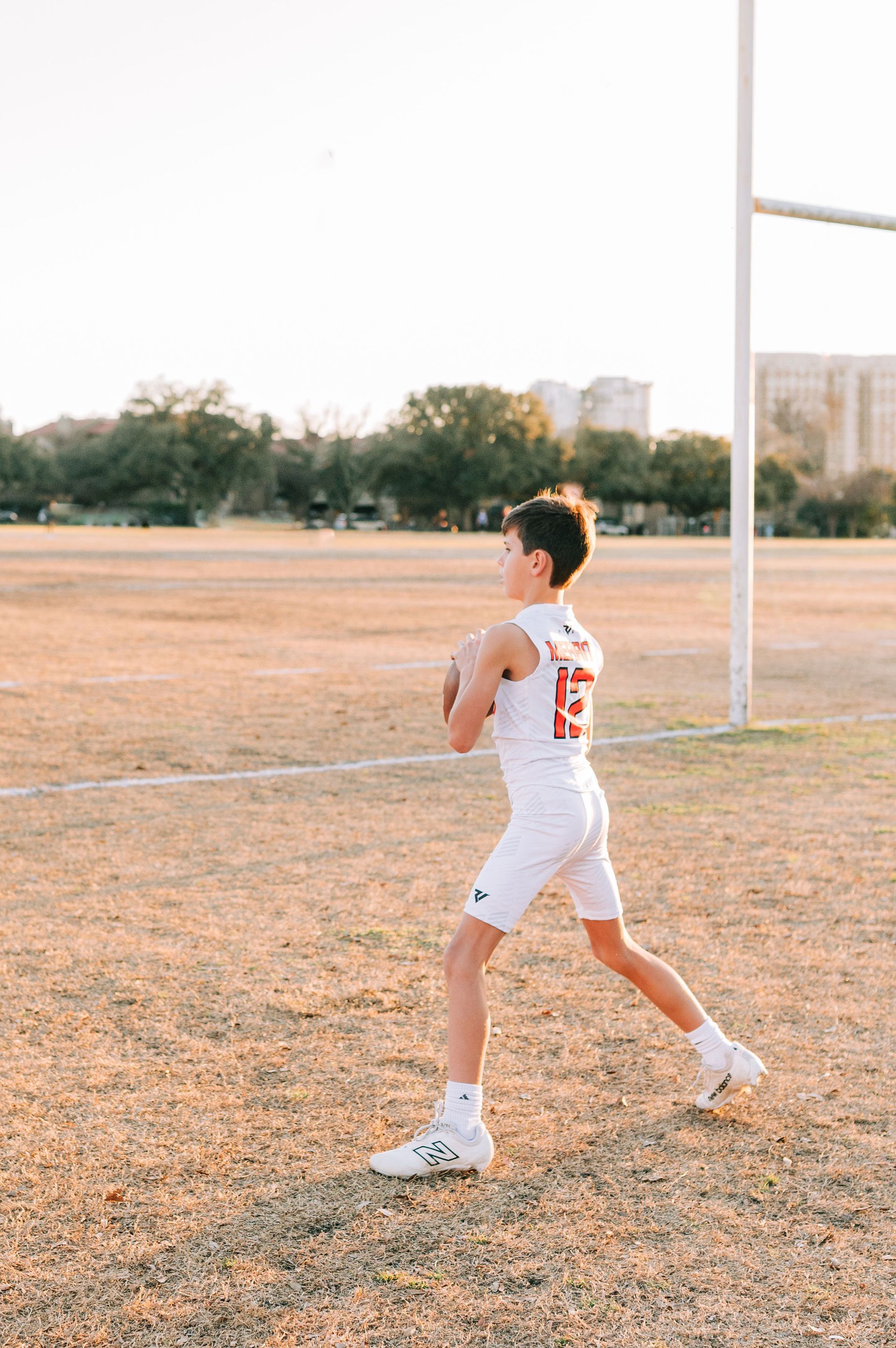 A young boy is throwing a football in a field.