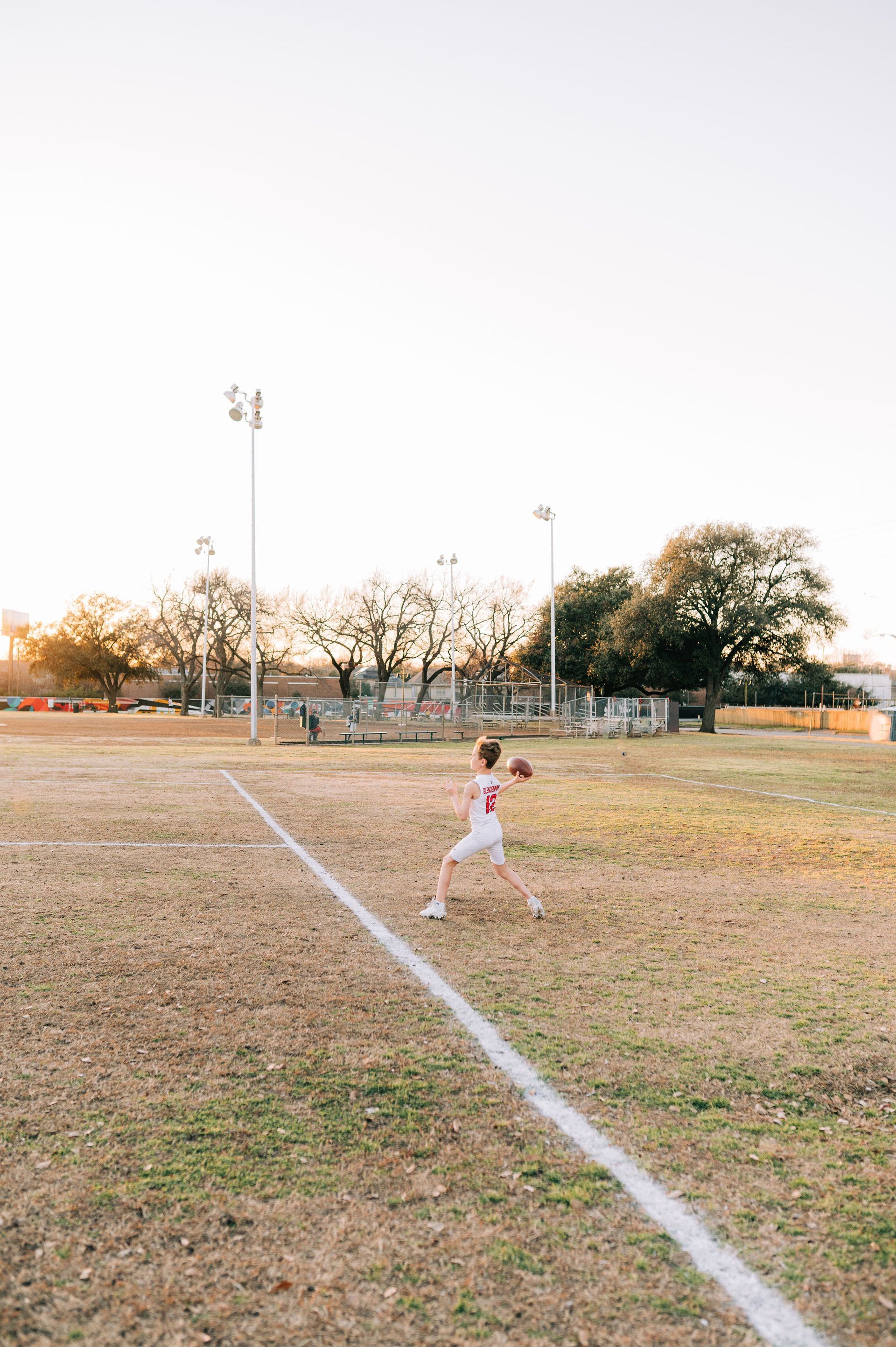 A young boy is throwing a football on a field.