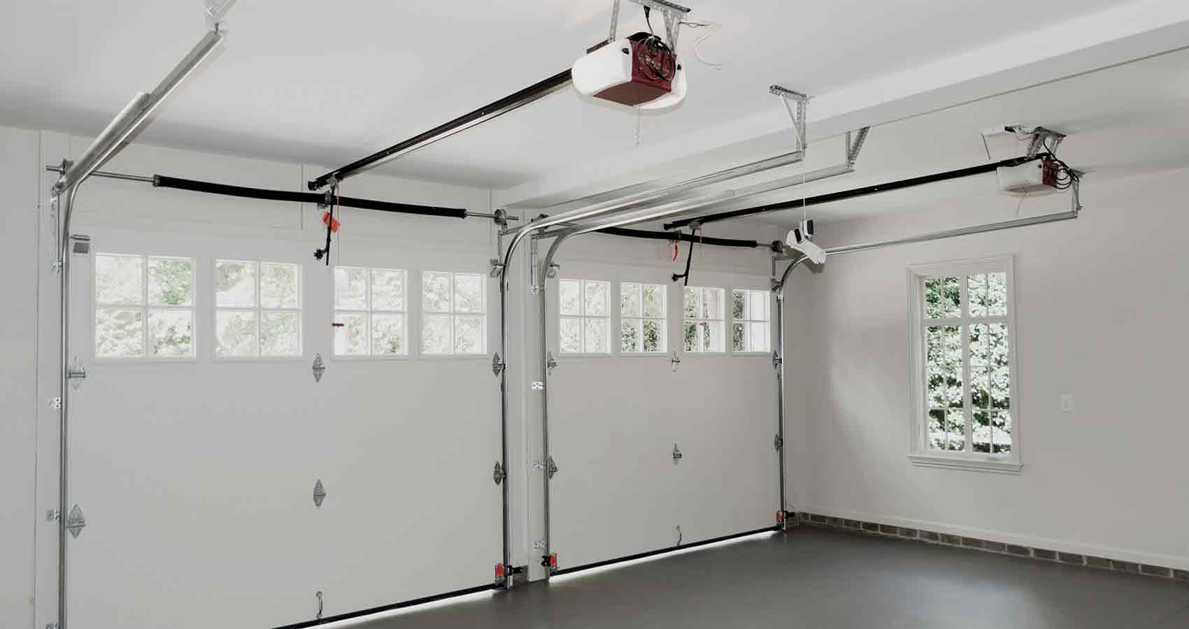 An empty garage with a garage door open and a window.
