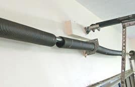 A close up of a garage door spring on a wall.