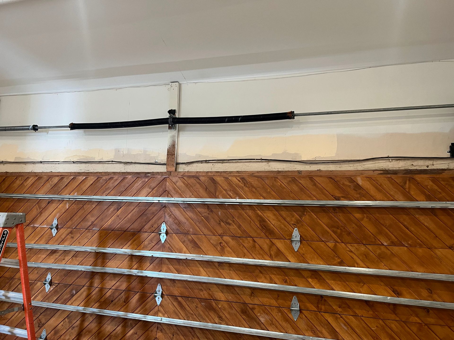 A close up of a garage door with a ladder in the background.