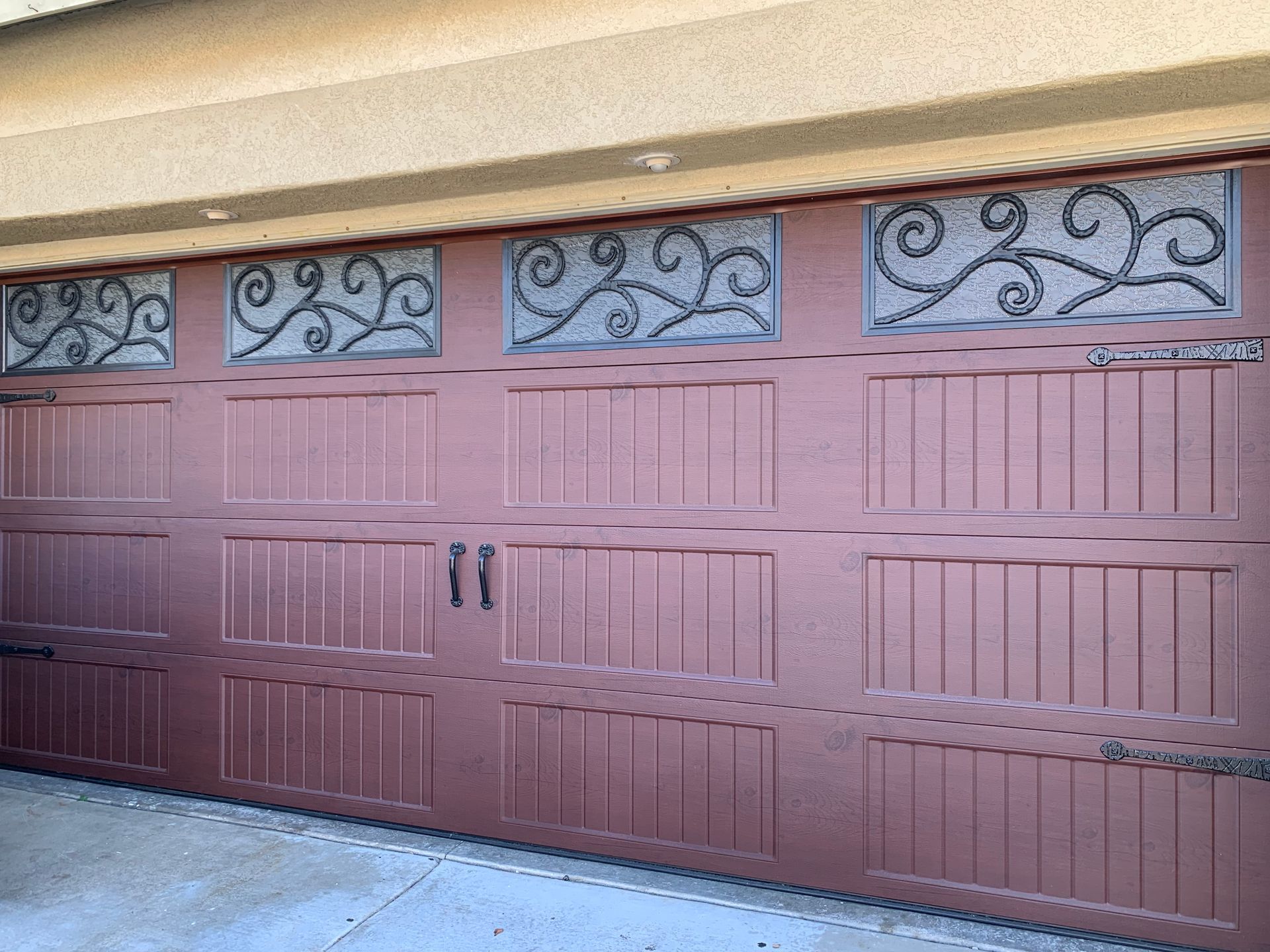 A red garage door with a wrought iron design on it.