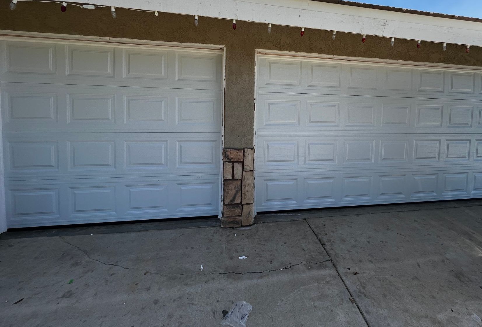 Two white garage doors are sitting next to each other on the side of a house.