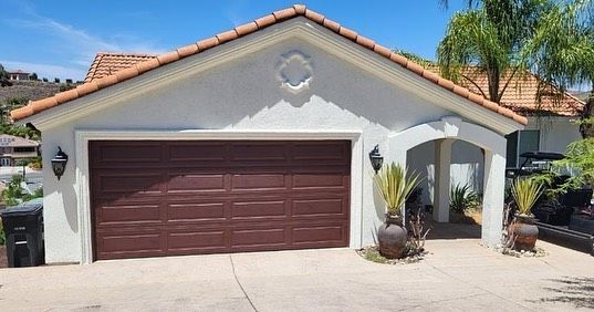A white house with a brown garage door and a tiled roof.