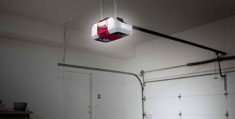 A red and white garage door opener is hanging from the ceiling of a garage.