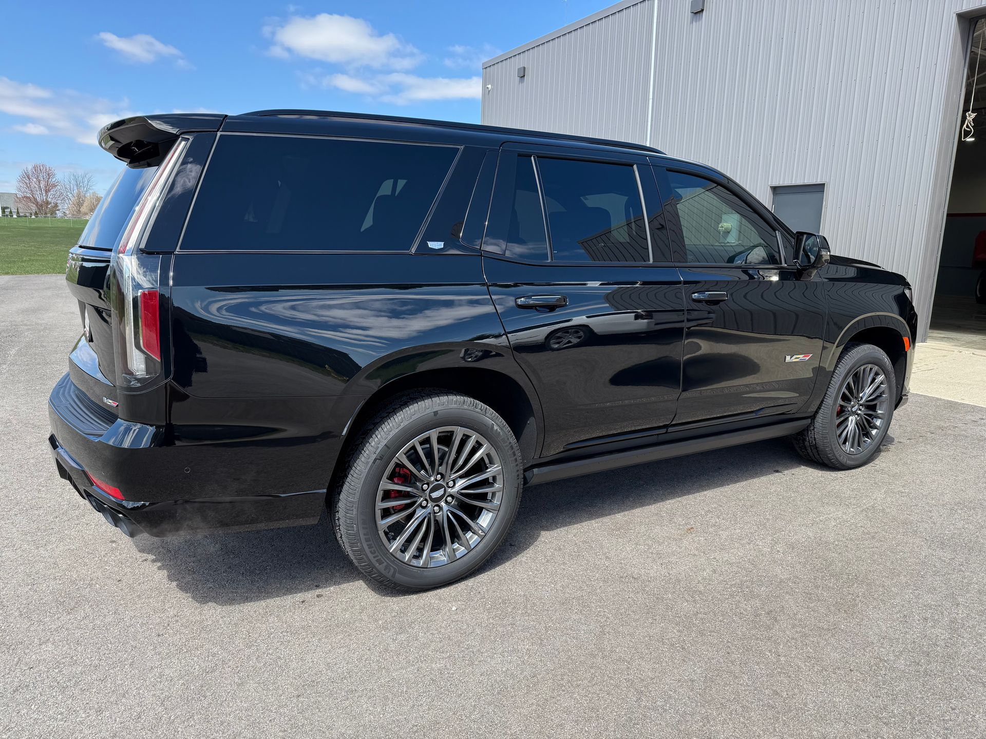 Black SUV, likely a GMC Yukon, parked outside a building on pavement.