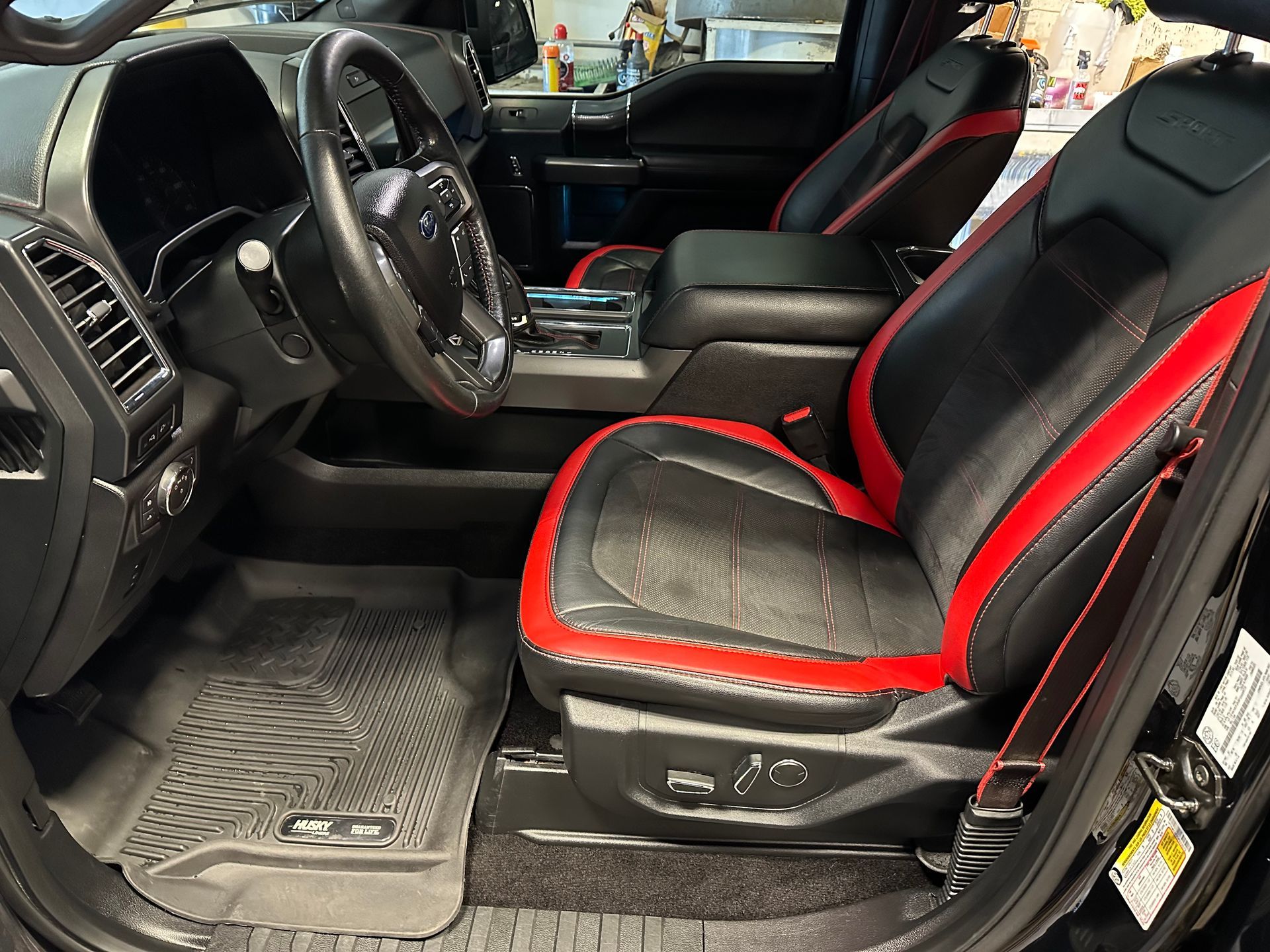 Black truck interior with red trim on black leather seats. Driver's side view.