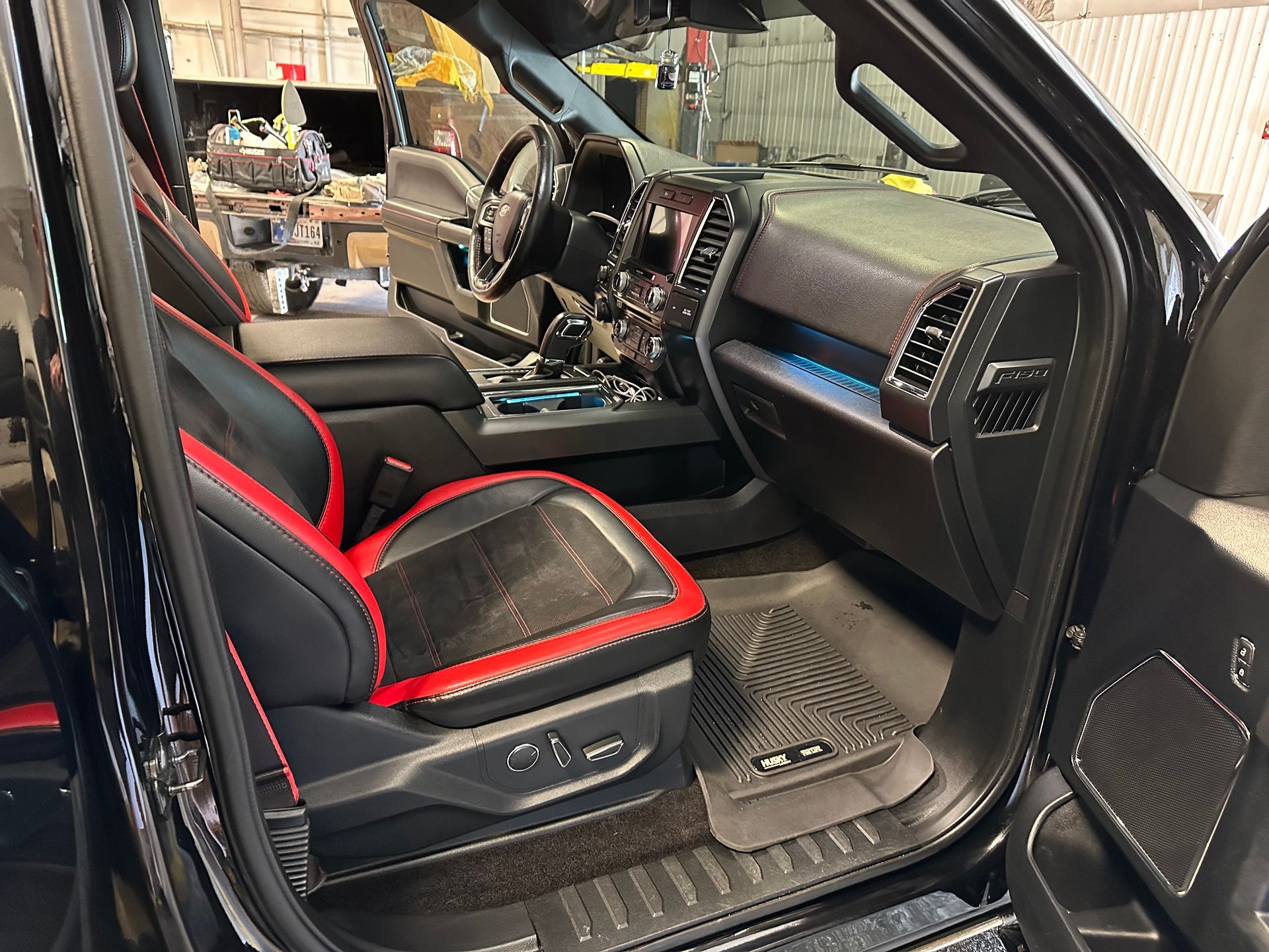 Interior of a black Ford pickup truck with red and black seats and rubber floor mats.