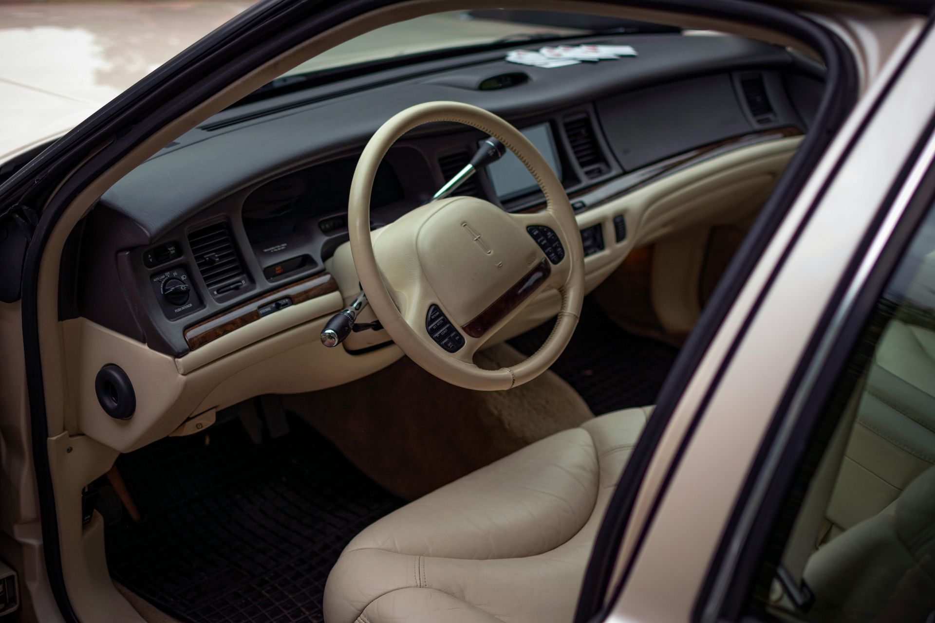 Interior view of a beige Lincoln sedan, showing the driver's seat, steering wheel, and dashboard.