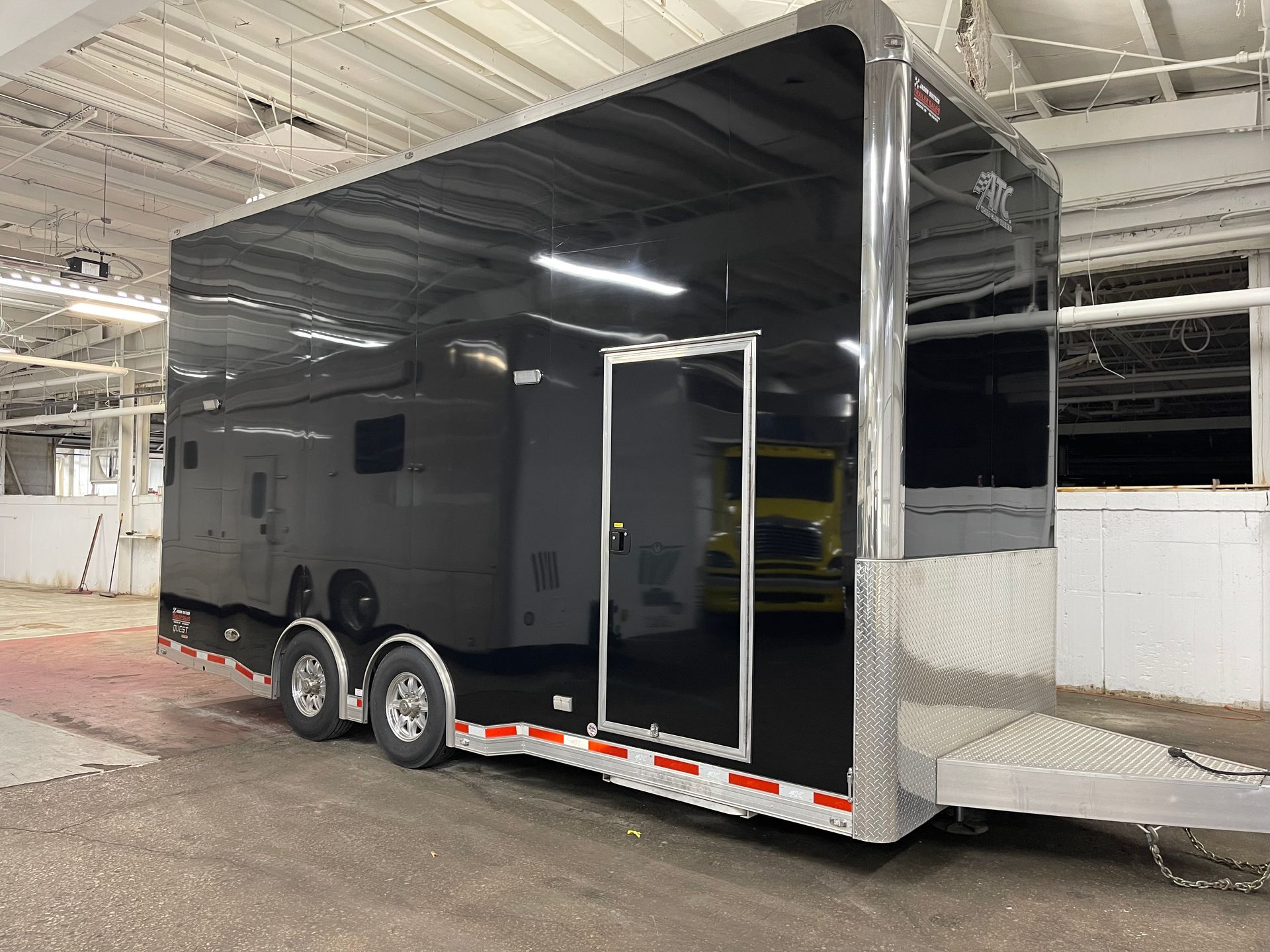 Black enclosed trailer with a silver front, parked indoors.