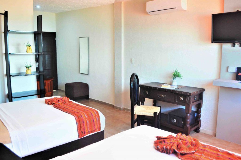 Habitación de hotel con dos camas, escritorio y TV de pared.