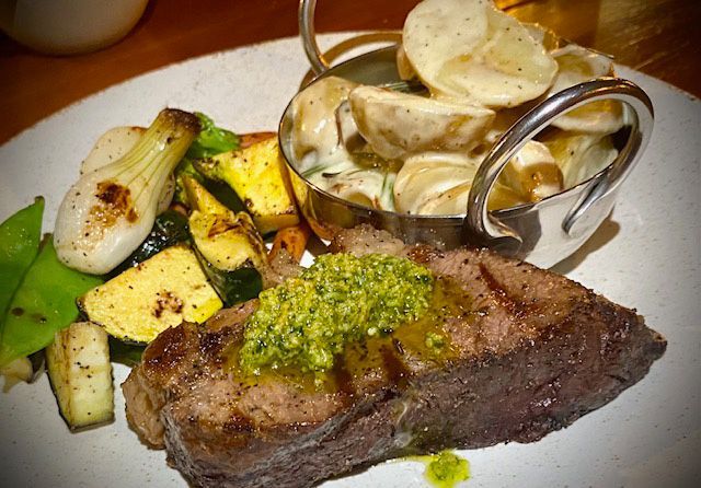 Grilled steak with pesto, roasted vegetables, and potato salad.