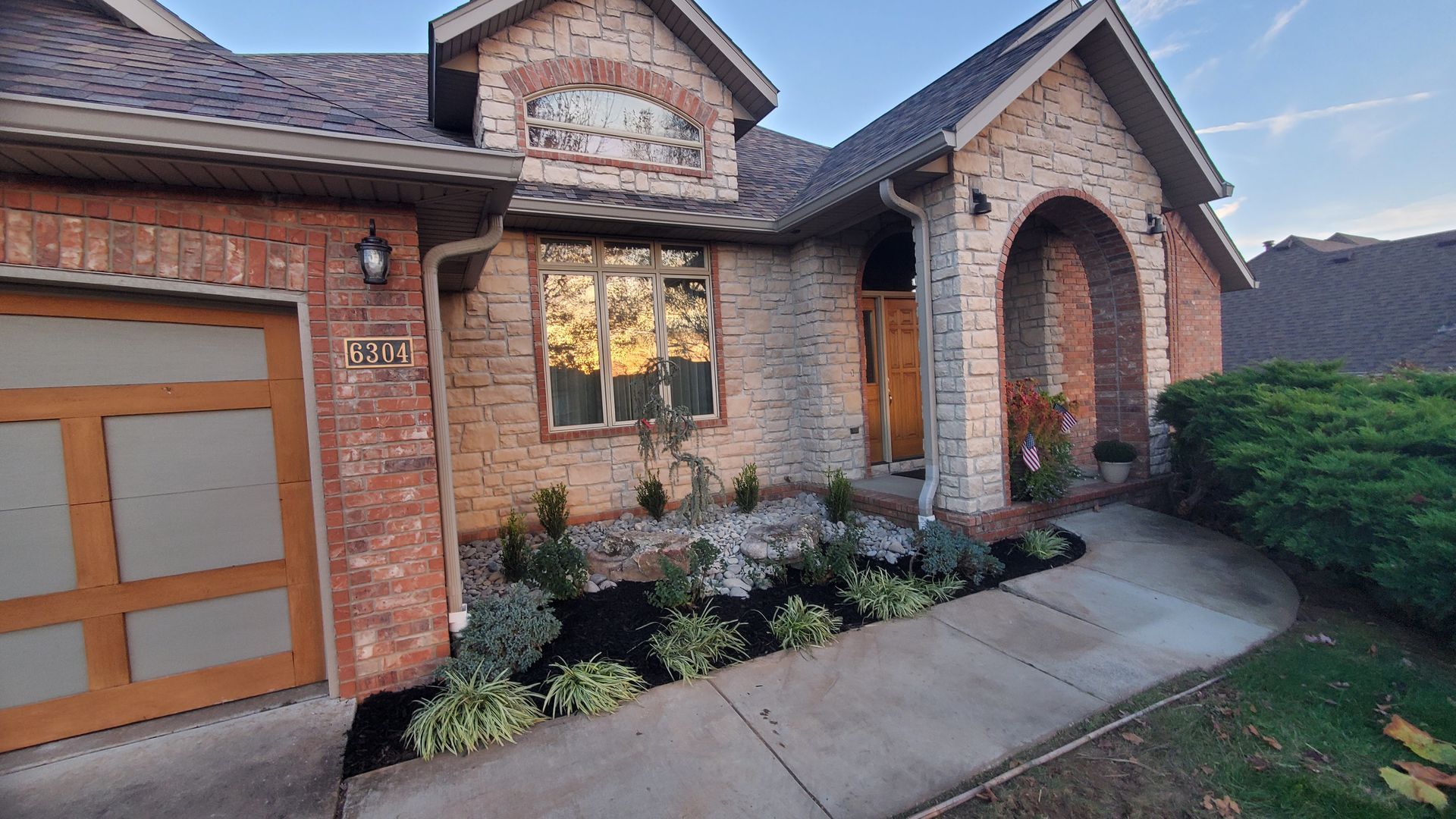 Brick house exterior with a landscaped yard and arched entryway.