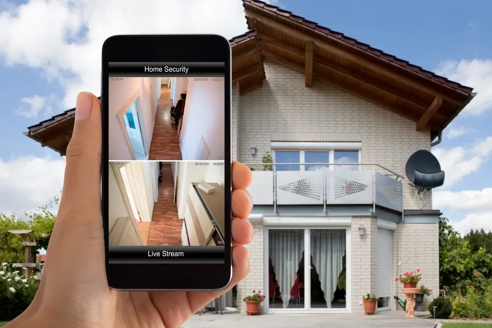 A person is holding a cell phone in front of a house.