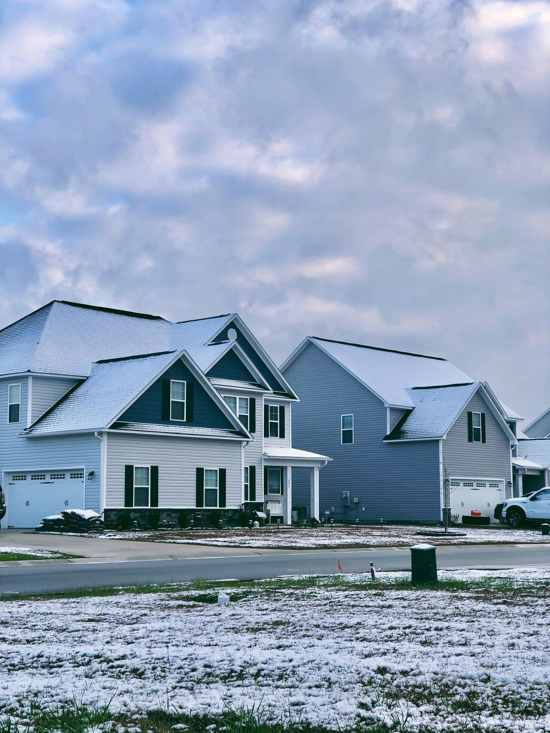 Suburban homes covered in snow under a cloudy sky.