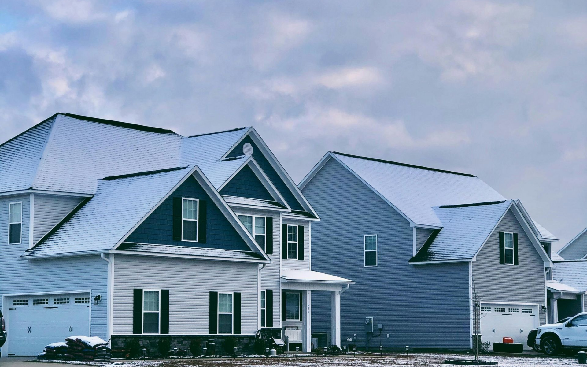 Houses with snow-covered roofs against a cloudy sky.