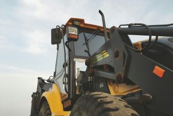 A yellow and black tractor is parked in a field.