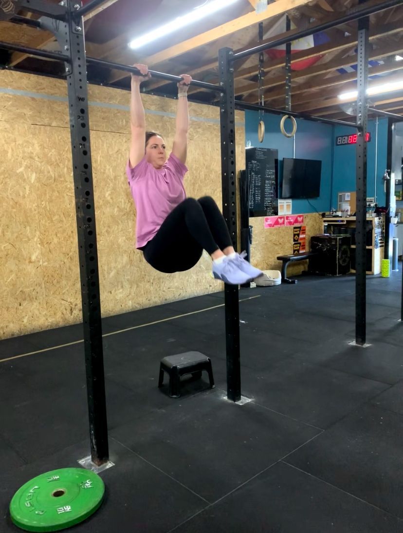 A woman is doing pull ups on a bar in a gym