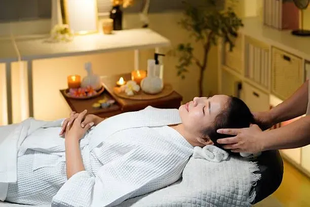 Woman enjoying a relaxing head massage with candles.