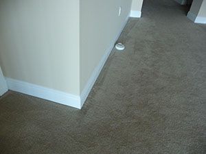 A smoke detector is sitting on the floor next to a wall.