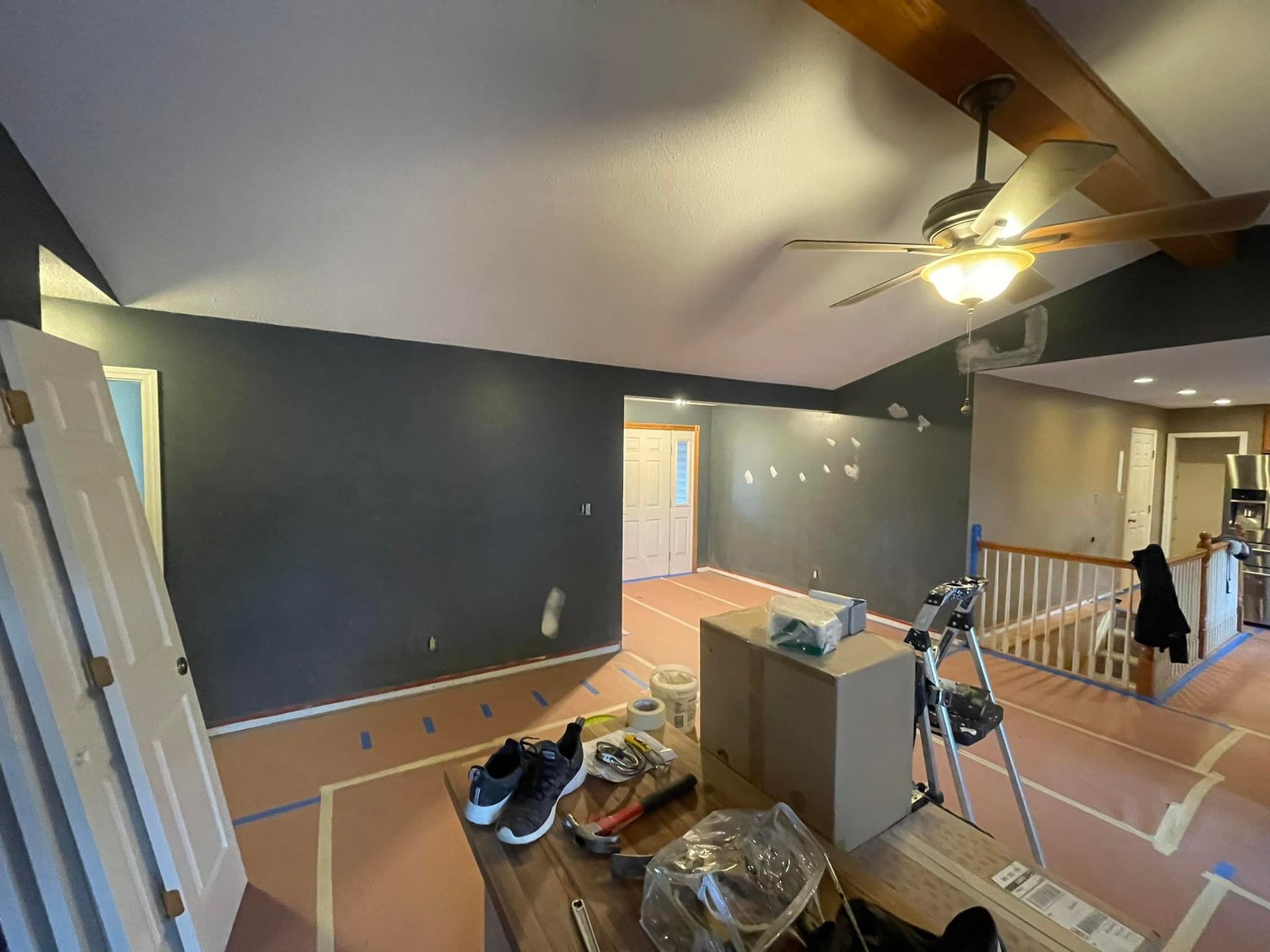 A living room with a ceiling fan and boxes on the floor.