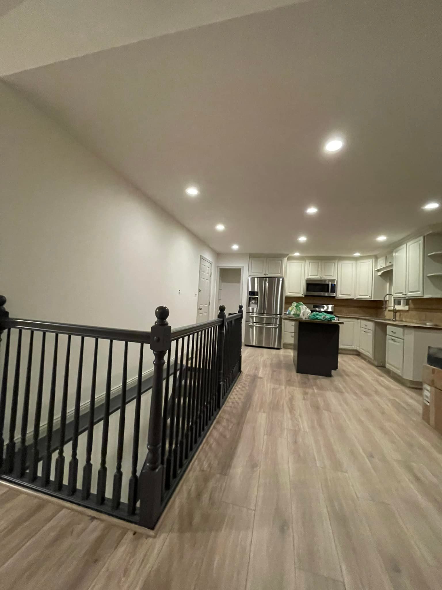 A kitchen with hardwood floors and a staircase leading to it.