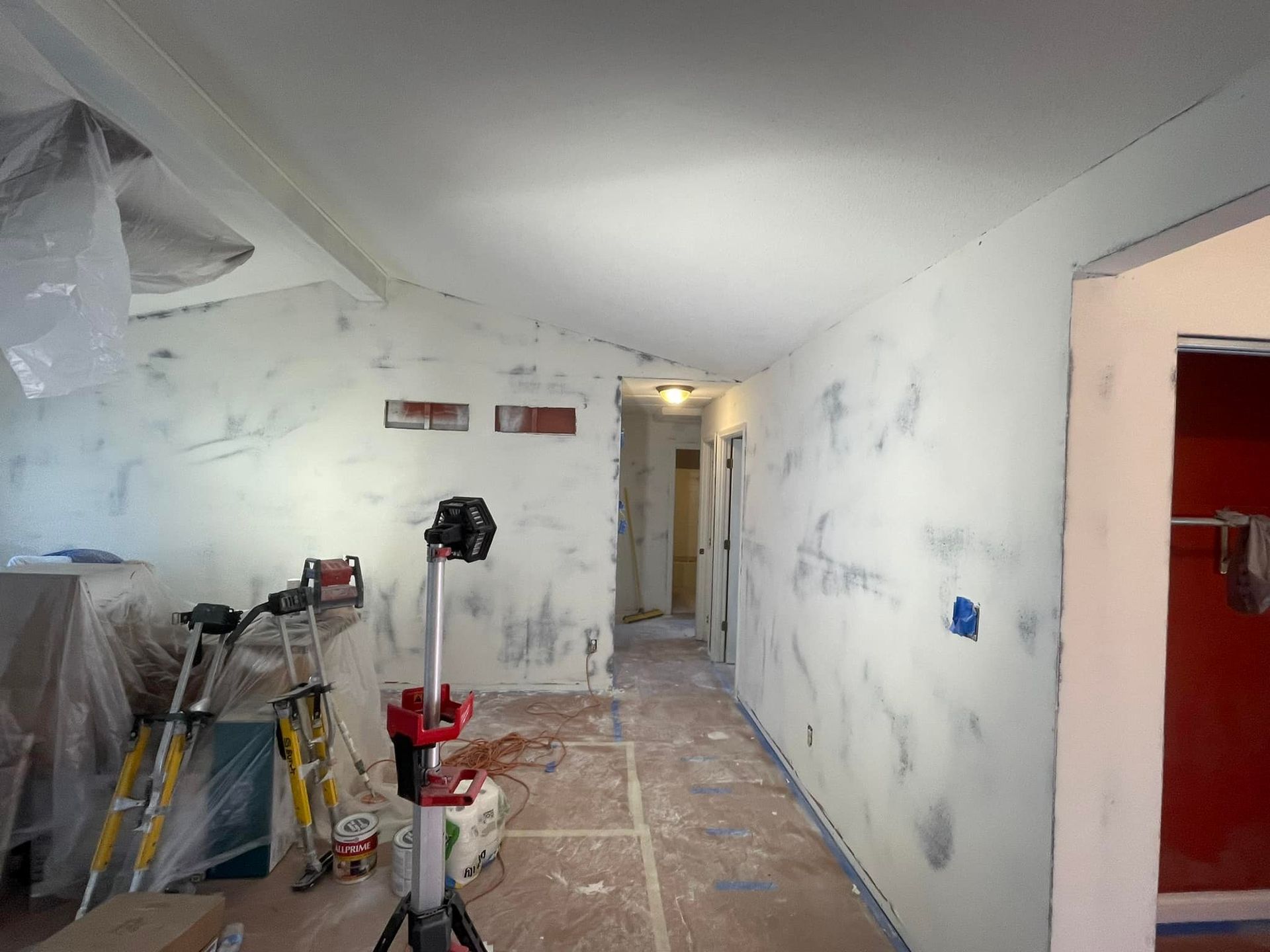 A room with a ladder and a light in it is being painted.