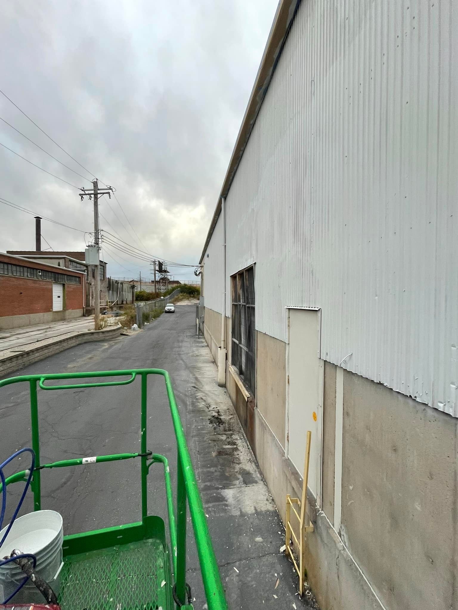 A green ladder is sitting next to a white building on the side of a road.