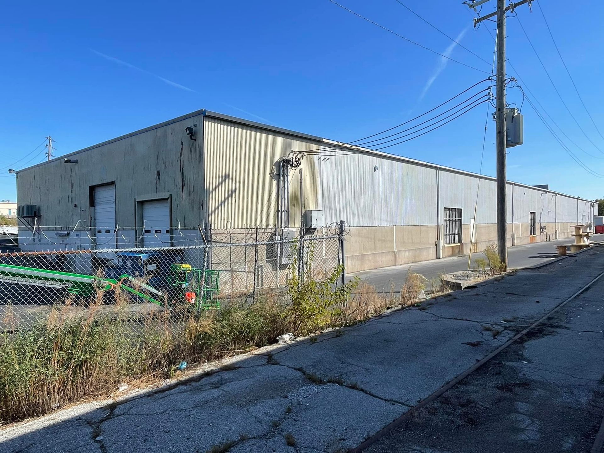 A large building with a fence around it and a tractor parked in front of it.