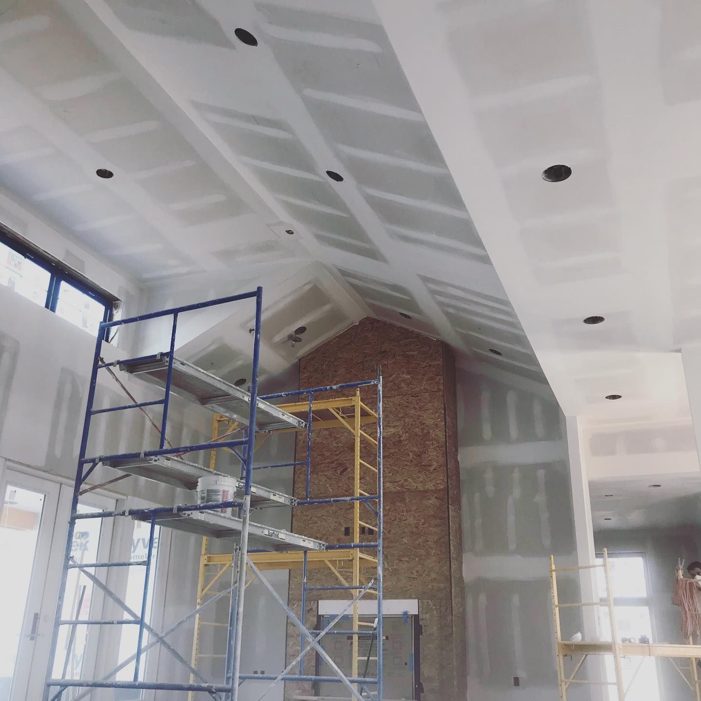 A large room with scaffolding and a brick fireplace