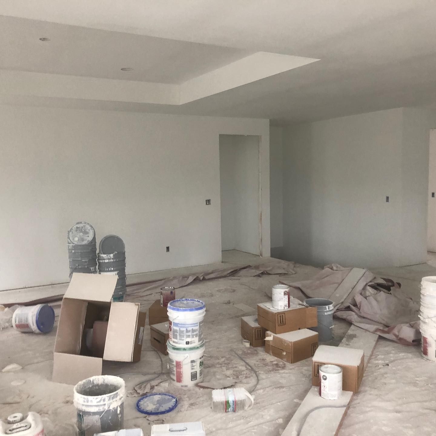 An empty room with buckets and boxes on the floor