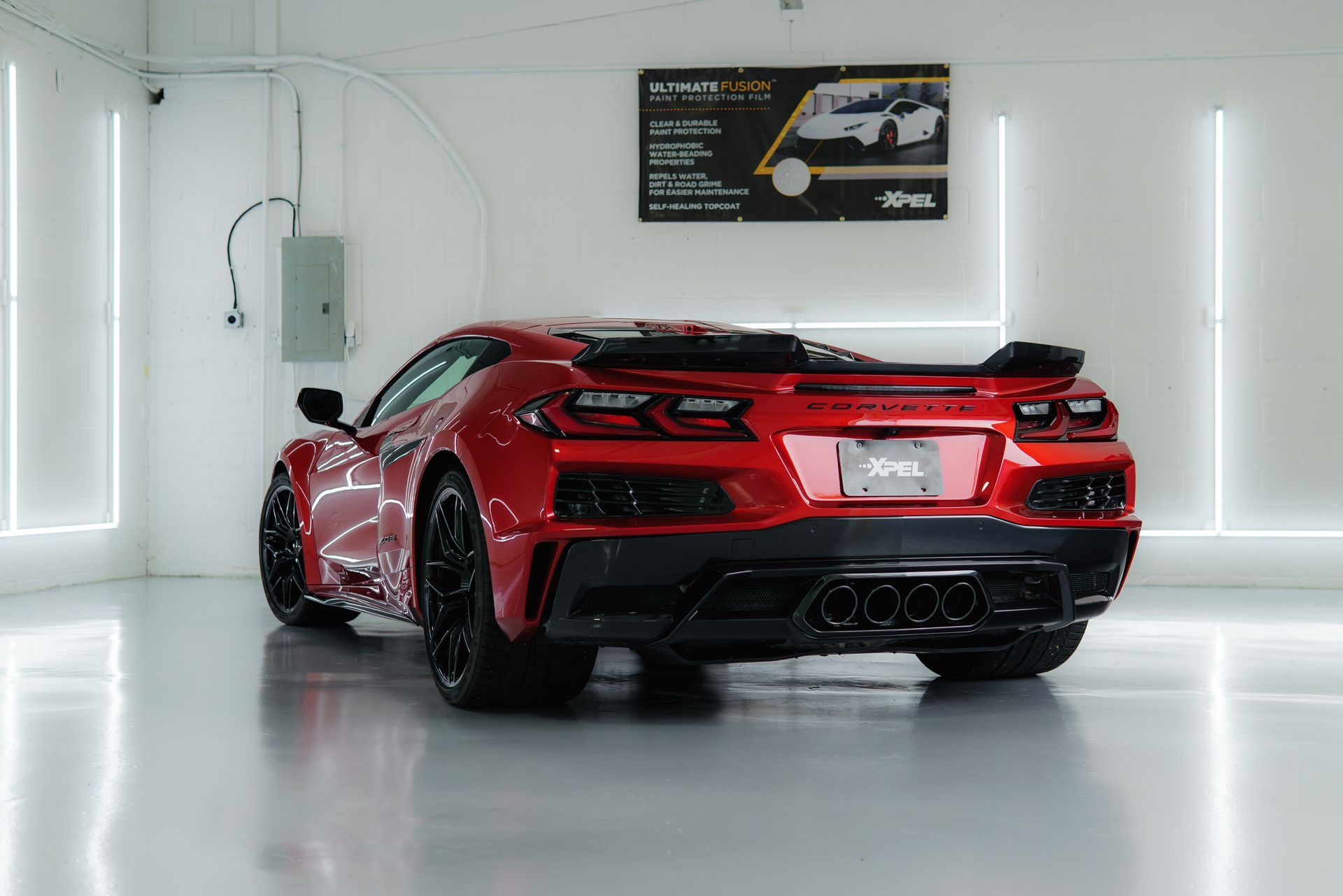Red sports car in a brightly lit garage; rear view.