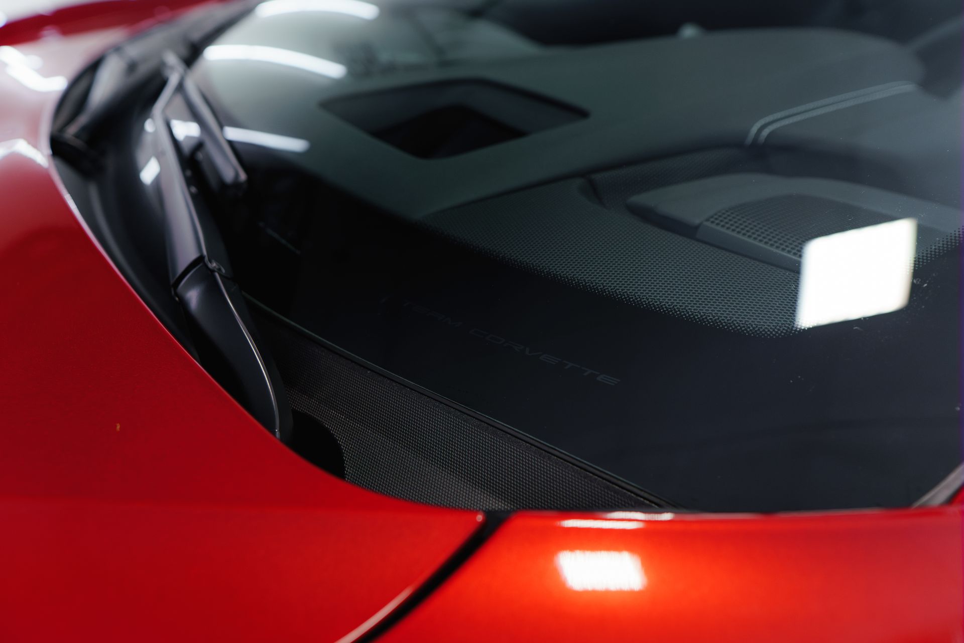Red car hood with windshield wipers and a black dashboard.