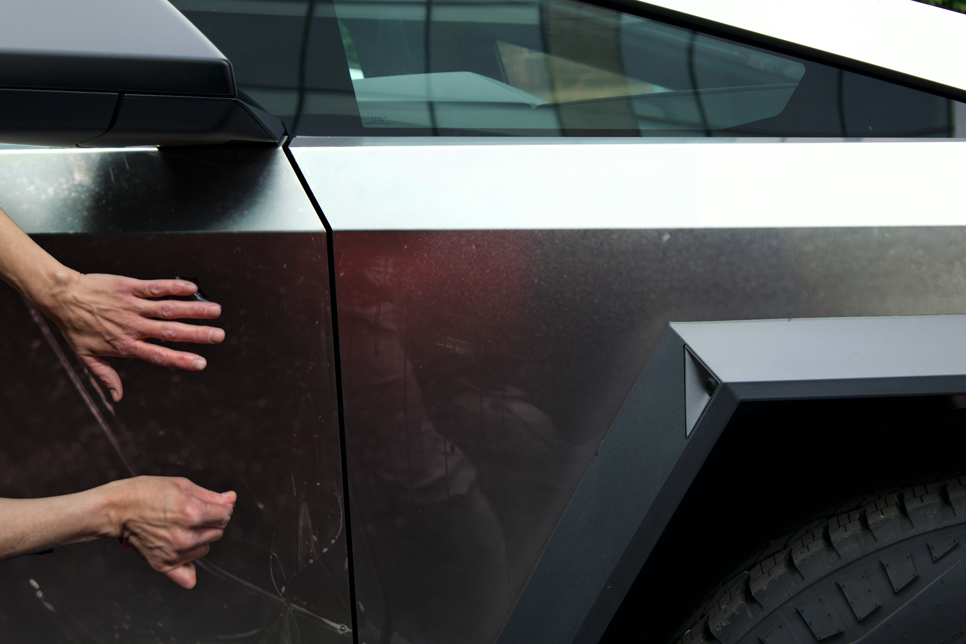 A person is touching the side of a car with their hands