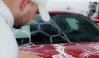 a man is washing a red car in a car wash .