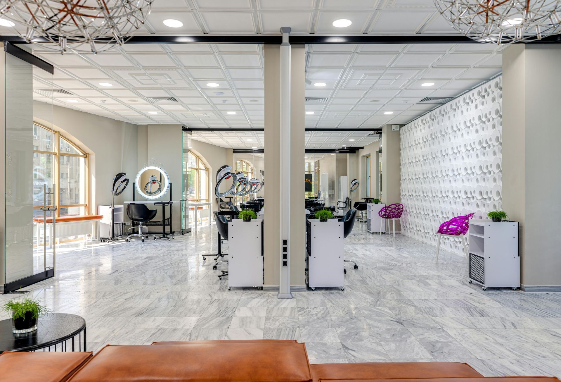 Bright, modern salon interior with mirrors, styling chairs, white decor, and plants