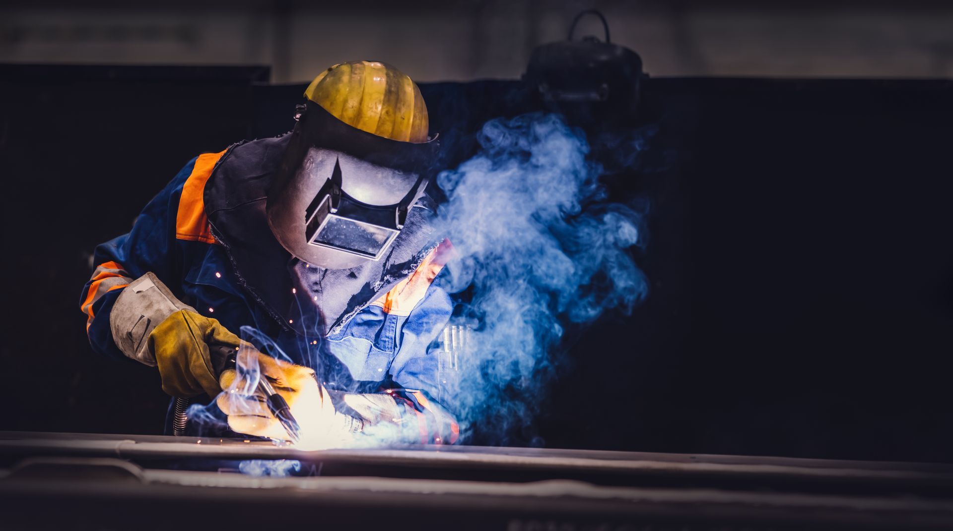 Welder using protective gear while working with bright sparks and smoke