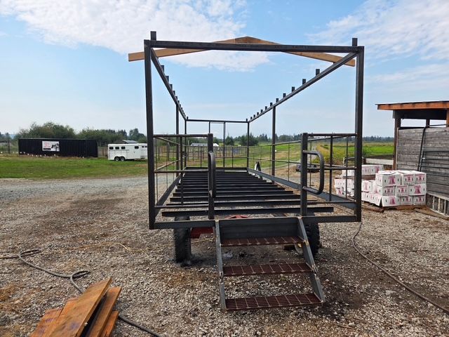 Steel frame of a tiny house on wheels, outdoors in a field, under a blue sky.