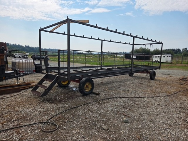 Metal frame structure on wheels, possibly a wagon or trailer. Black metal, yellow wheels, outdoors.