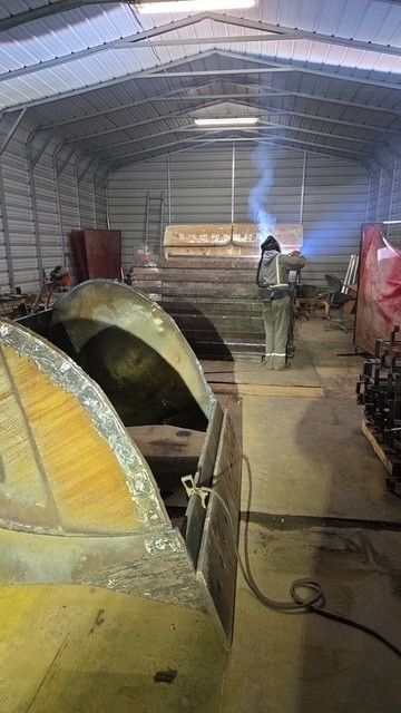 Welder in a workshop, sparks flying. A yellow metal object is in the foreground.