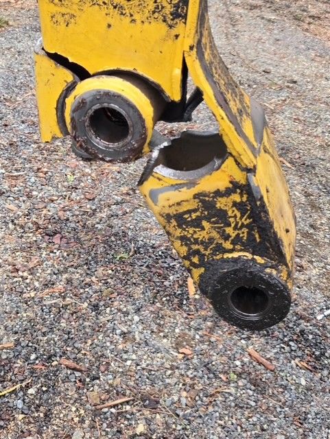 Broken yellow metal machinery parts on gravel.